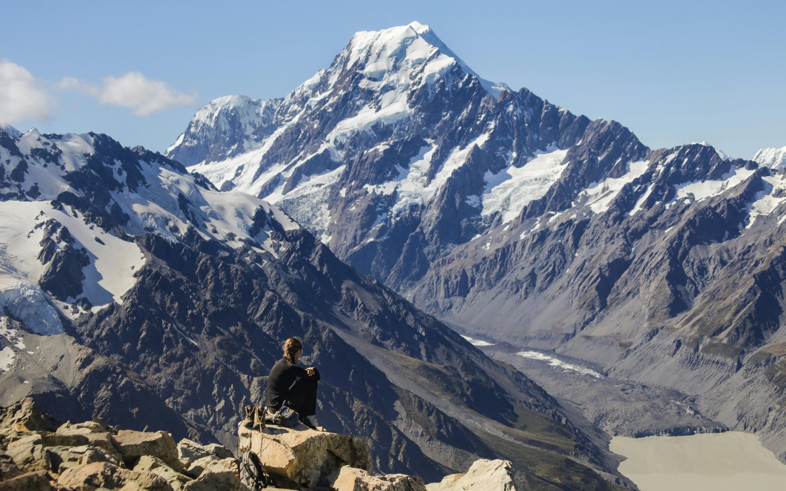 A hiker resting while overlooking the majestic Mount Cook in New Zealand's Southern Alps.